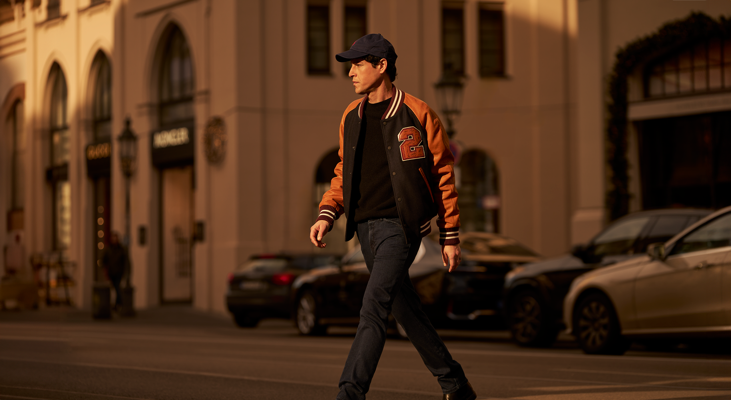 Man walking on a city street with buildings and cars in the background